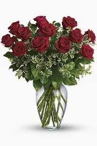 always in mind - Deep, velvety red roses gathered in a clear glass vase create an immediate impression of timeless devotion-perfect as a romantic bouquet for anniversaries or Valentine's Day, or a respectful sympathy arrangement when you want someone to feel truly remembered. The rich red-and-green contrast reads classic and formal, the kind of floral gift that makes the person you're thinking of feel honored and seen.  About a dozen full, rounded red roses sit atop a dense bed of mixed greenery and variegated filler, forming a lush, layered base that emphasizes each bloom. The arrangement's compact, vase-centered design keeps attention on the roses' texture and color while the clear glass vase lends simple elegance and lets the stems show through for a clean finish.  Whether you're marking a milestone in love or offering comfort, this arrangement carries a clear message of enduring care. Arrives ready to display in the included clear glass vase; refresh water and trim stems every few days to prolong bloom life.