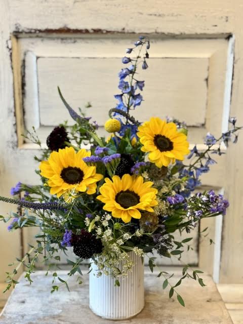 Summer Sunshine - A white washed metal vase holds a summer fresh design featuring sunflowers. This arrangement is sure to make someone's day!
