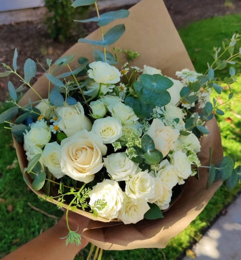 Bouquet of white roses with eucalyptus wrapped in brown paper