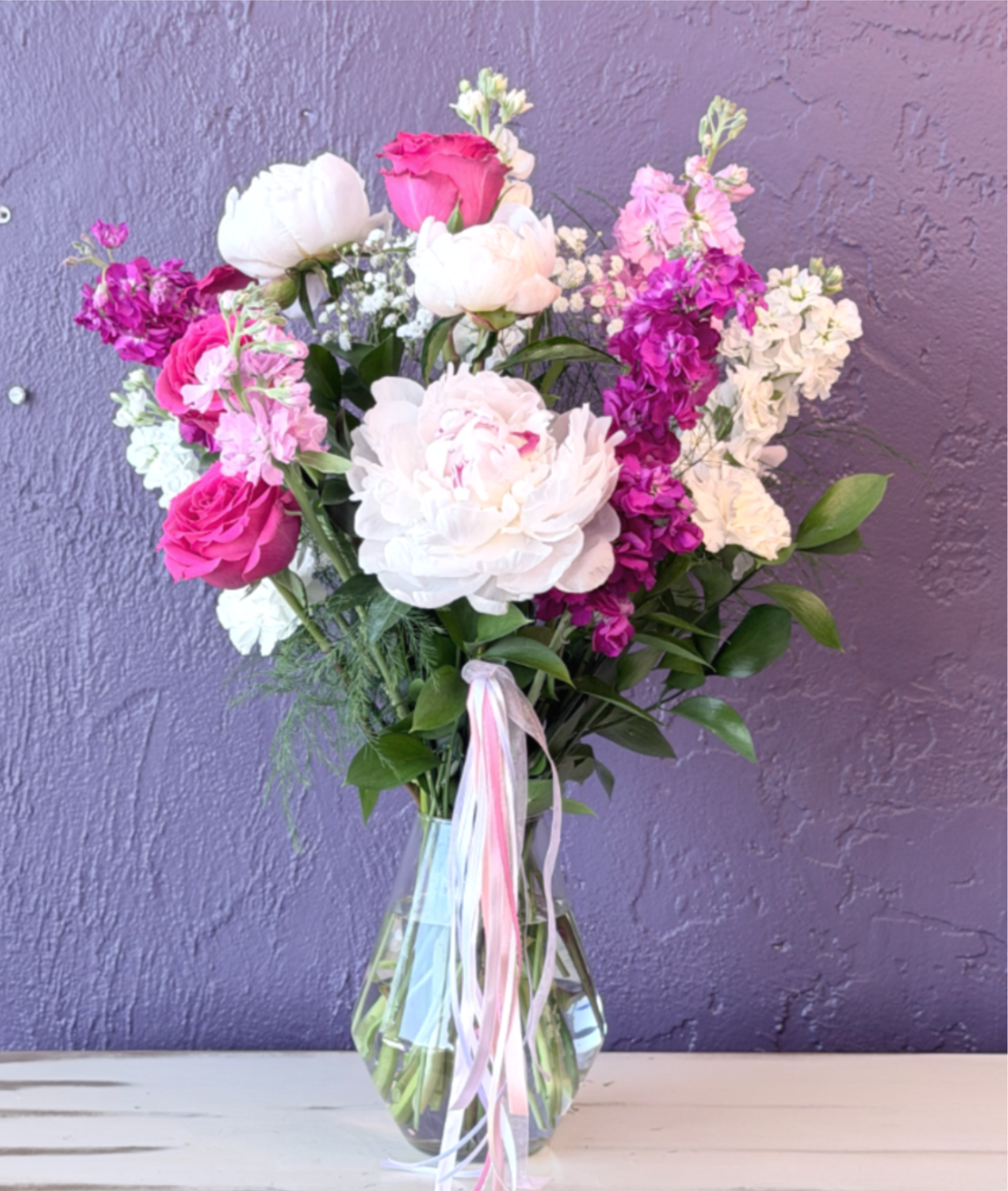 Pink and white bouquet in a clear glass vase with ribbon