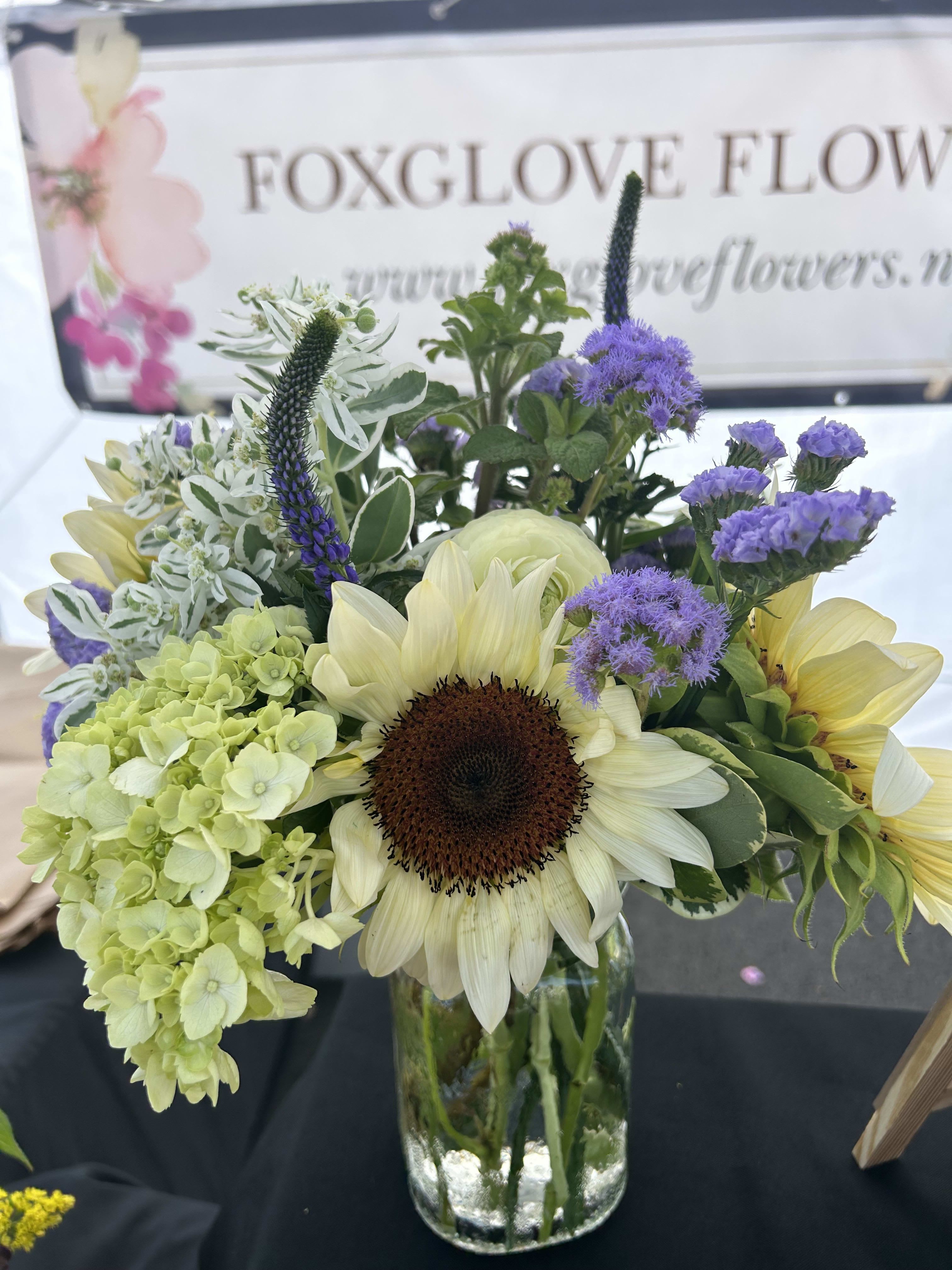 Sunflower and hydrangea bouquet in a glass vase with purple accents