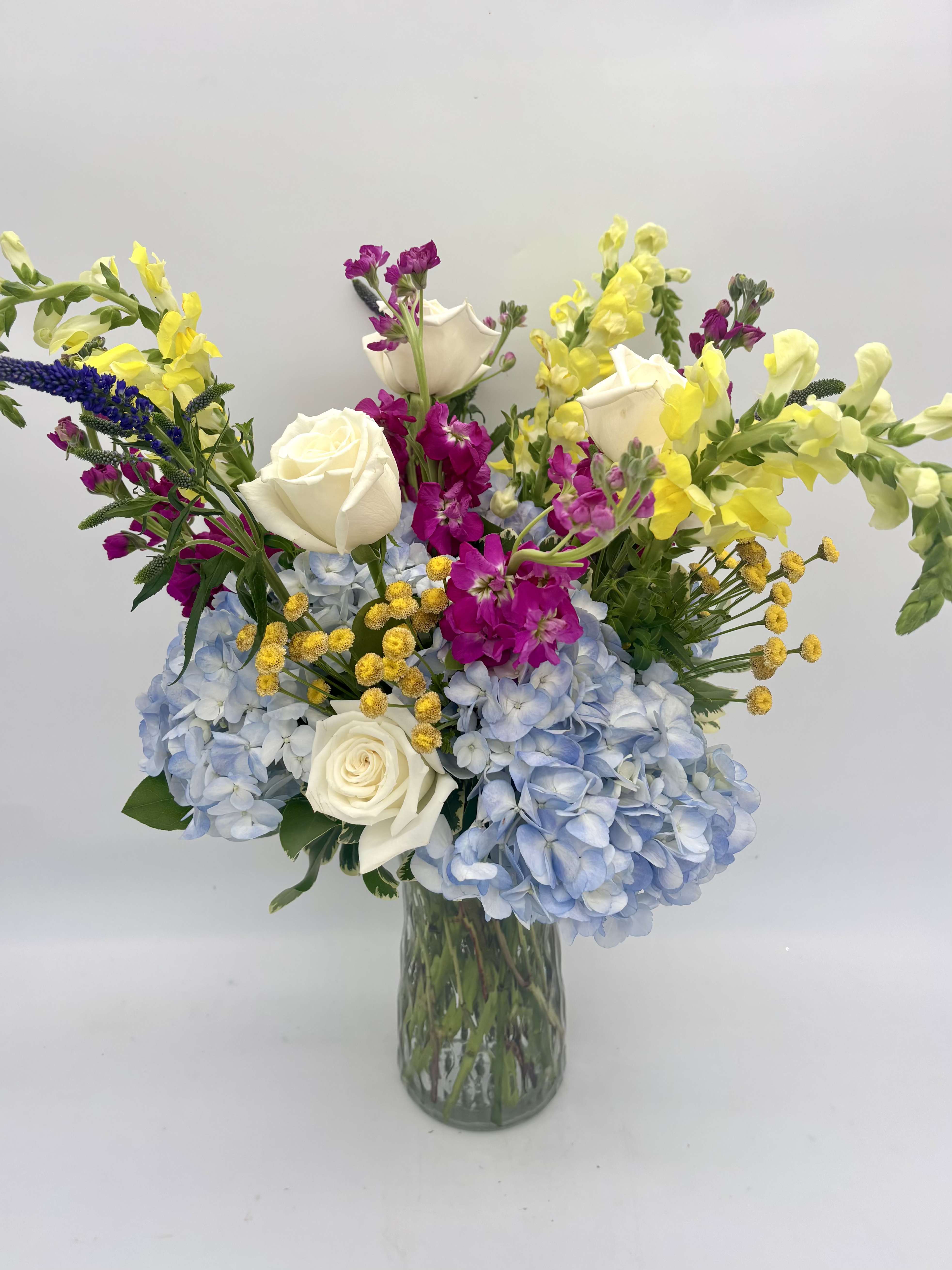 SPECIAL OF THE WEEK - Our special of the week is created from seasonal summer flowers and emphasizes our signature Topiary look - lush, intentional, and garden-inspired. Originally $175, NOW $125. Dreamy blues and deep fuchsias complimented with bright pops of yellow. ***ONE OF A KIND*** 