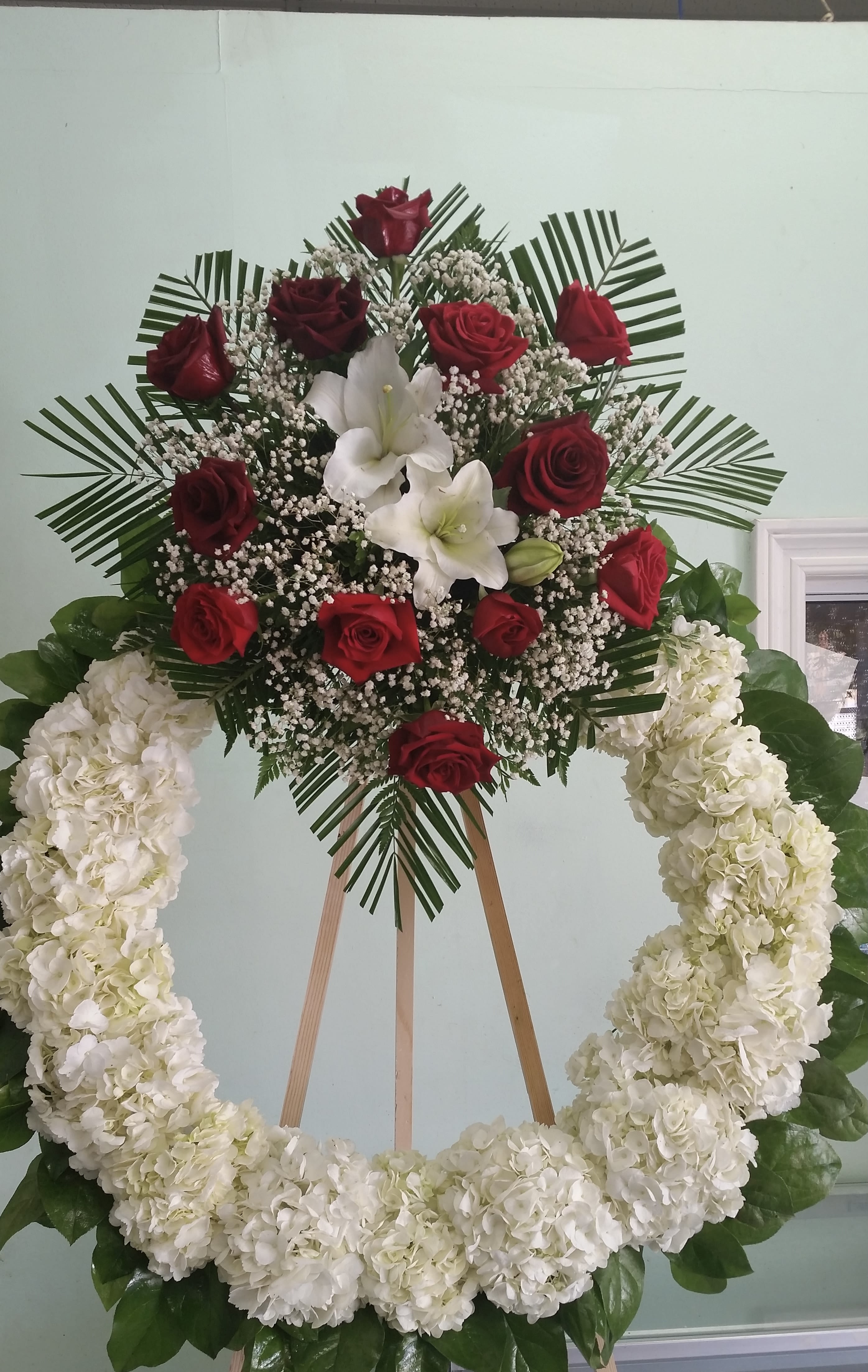 Standing floral wreath with red roses, white lilies, and white hydrangeas