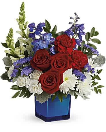 Red roses, white daisies, and blue flowers in a blue glass vase