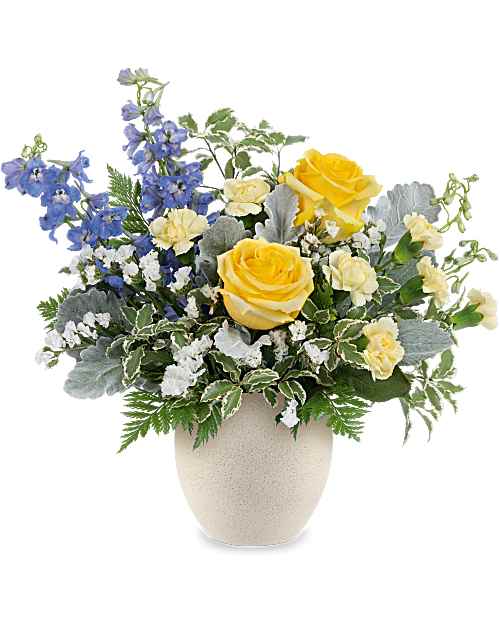 Coastal Bloom Bouquet - Bring breezy style to any Day with the Coastal Bloom Bouquet, a fresh mix of blue, yellow, and white blooms arranged in Teleflora's Modern Stone Bowl. The faux concrete speckled finish gives this gift cool, coastal-inspired appeal. A fresh floral arrangement featuring light yellow roses, miniature light yellow carnations, blue delphinium, and white sinuata statice, accented with dusty miller, and premium greens.