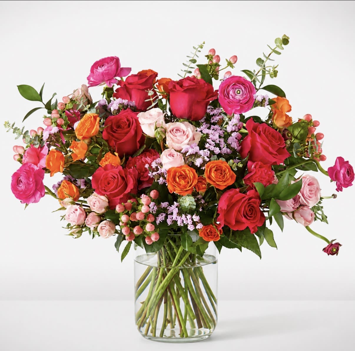 Bright Delight  - Bright Delight is vibrant, garden-style arrangement featuring a mix of seasonal blooms in warm and soft tones, accented with fresh greenery for a natural, airy feel. Designed in a clear glass vase to showcase the stems, this piece offers an organic, loosely gathered look. Flower varieties and colors may vary based on availability while maintaining the overall style and palette.