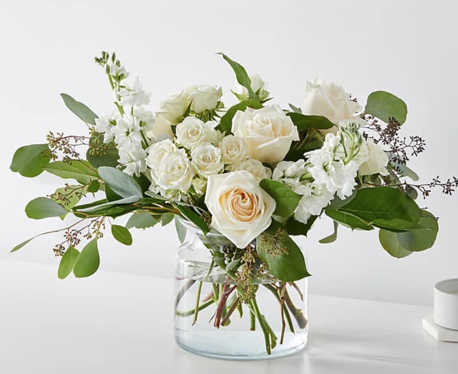 White roses and stock in a clear glass vase