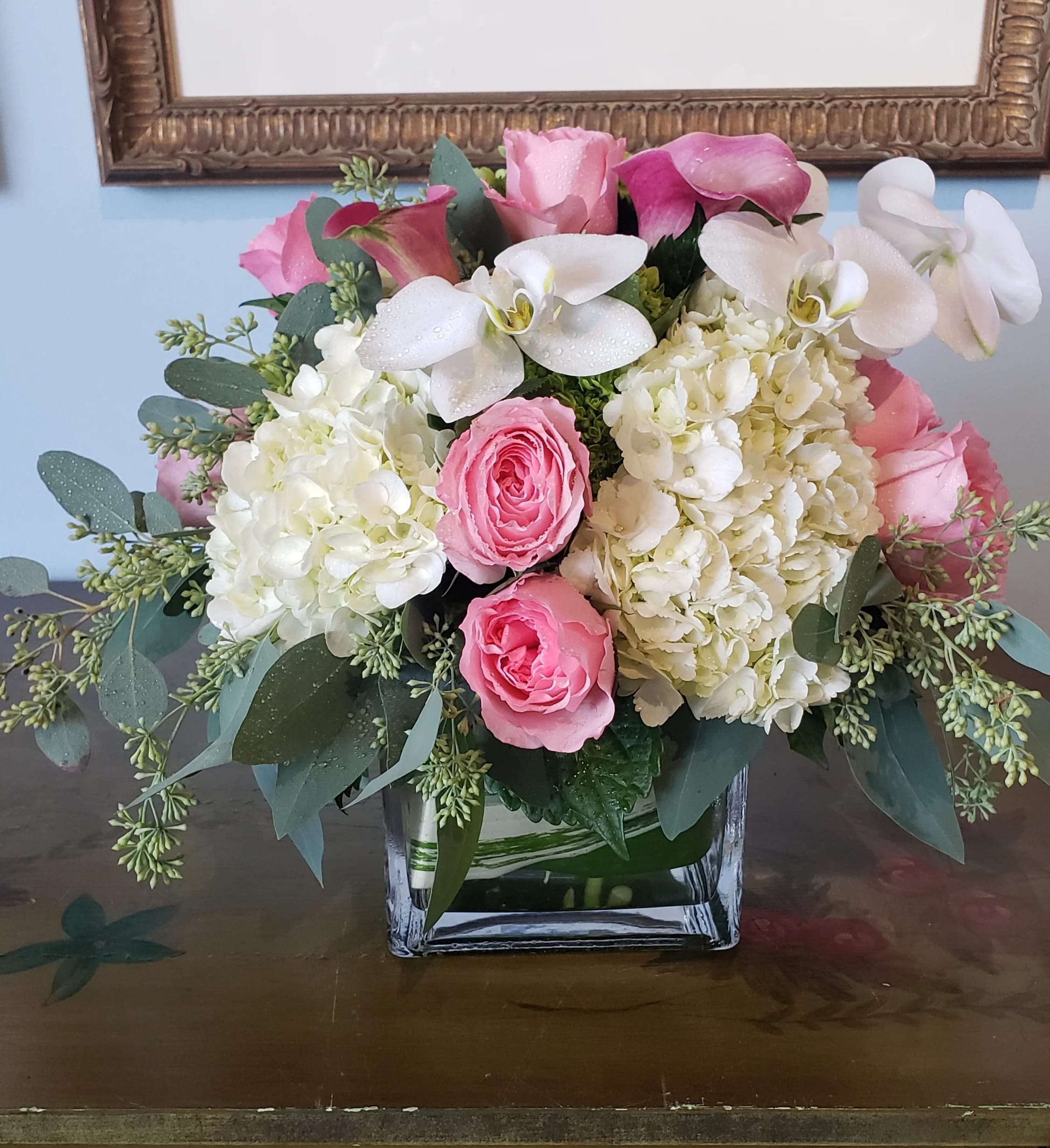 Simply Gorgeous - Sometimes the most beautiful things are the simplest. Simply Gorgeous proves elegance doesn’t have to be complicated, featuring soft white hydrangeas, delicate pink roses, pure white Phalaenopsis orchids, and seeded eucalyptus—artfully arranged for a stunning yet understated look. Perfect for any occasion, from meaningful milestones to heartfelt gratitude.  Please note: Seasonal flowers may vary based on availability, ensuring each arrangement is unique and fresh.  Freshness Guarantee: We stand behind our quality. Your flowers are guaranteed to look fresh and beautiful for 3–5 days from delivery.  To help them last:  •Top off the vase with clean water daily.  •Keep arrangements away from direct sun, heat, and drafts.  •Trim stems slightly after a couple of days if possible.