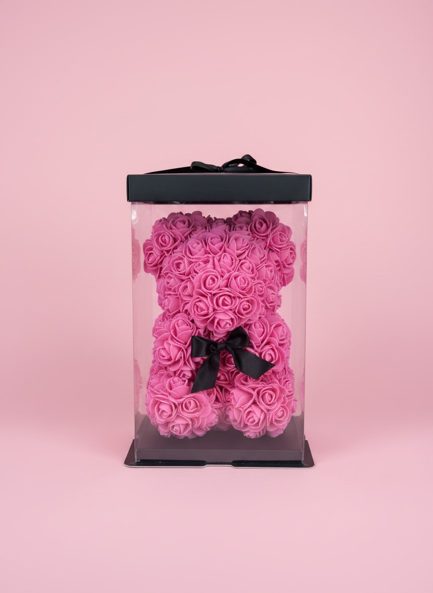 Rose Bear - A whimsical teddy bear crafted entirely from tightly packed pink roses makes this flower arrangement an unforgettable gift for anniversaries, Valentine's Day, or to delight the person you're thinking of. The rose bear's playful yet romantic silhouette reads feminine and joyful-she'll feel specially celebrated the moment the clear gift box is opened.  Each tiny bloom is arranged in a dense, monochrome pink surface that highlights the roses' soft, velvety texture. The bear sits inside a clear rectangular plastic gift box with a black base and matching black lid, finished with a sleek black ribbon for a polished presentation that's ready to give.  Perfect for someone who loves cute, stylish keepsakes rather than a traditional bouquet, this rose bear works well as a romantic surprise, a birthday treat, or a thoughtful pick-me-up. No watering is needed; the boxed presentation keeps the roses secure for gifting and display-order with confidence for same-day or scheduled delivery where available.