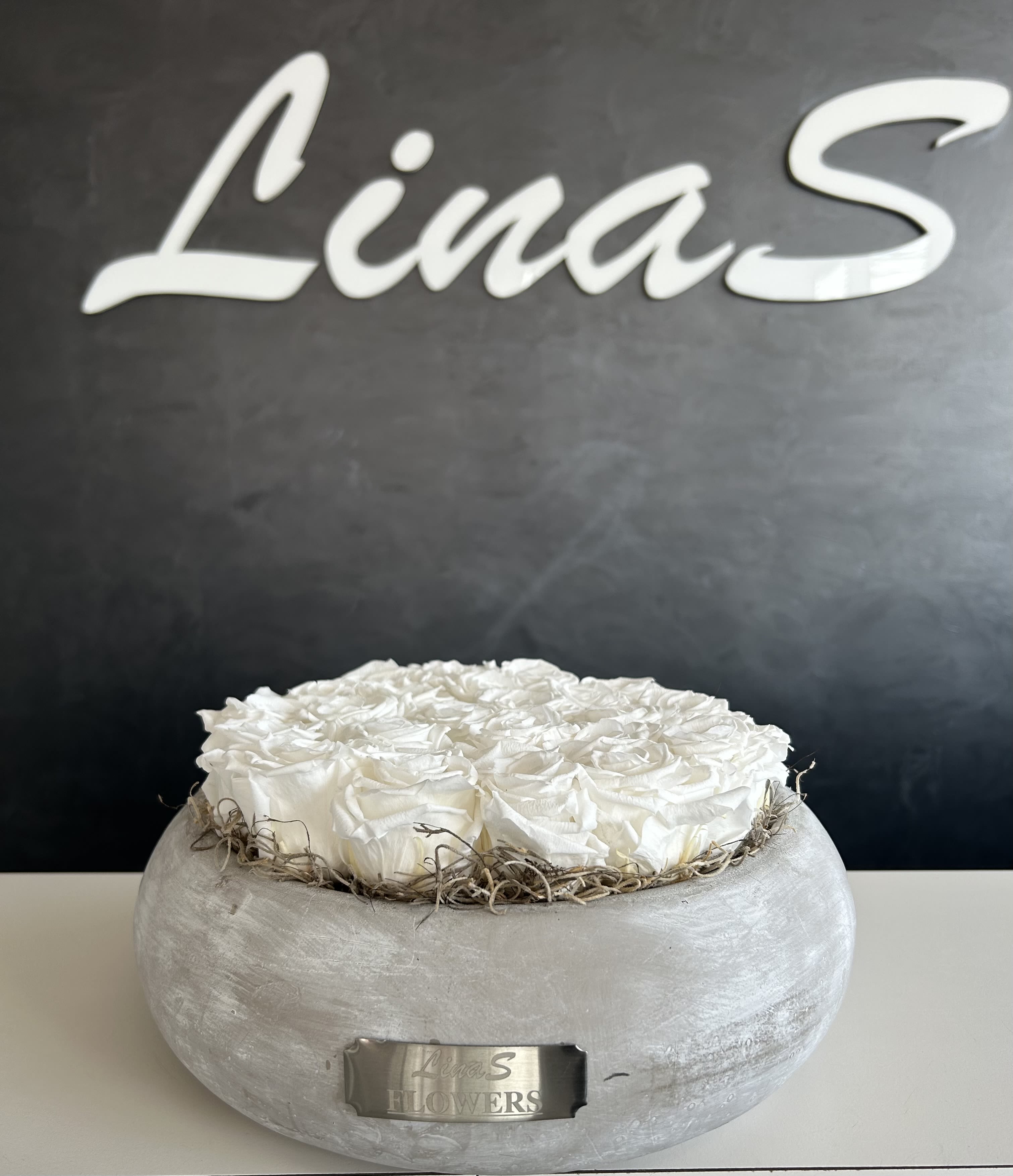 White roses arranged in a round gray container