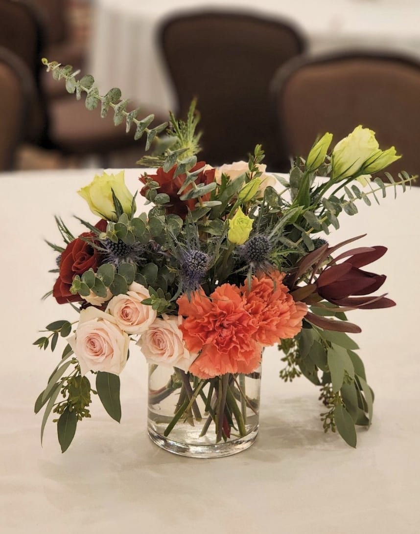 Mixed bouquet in a clear glass vase with roses, carnations, and greenery