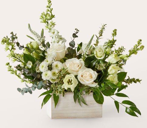 White roses and pale green flowers in a wooden box