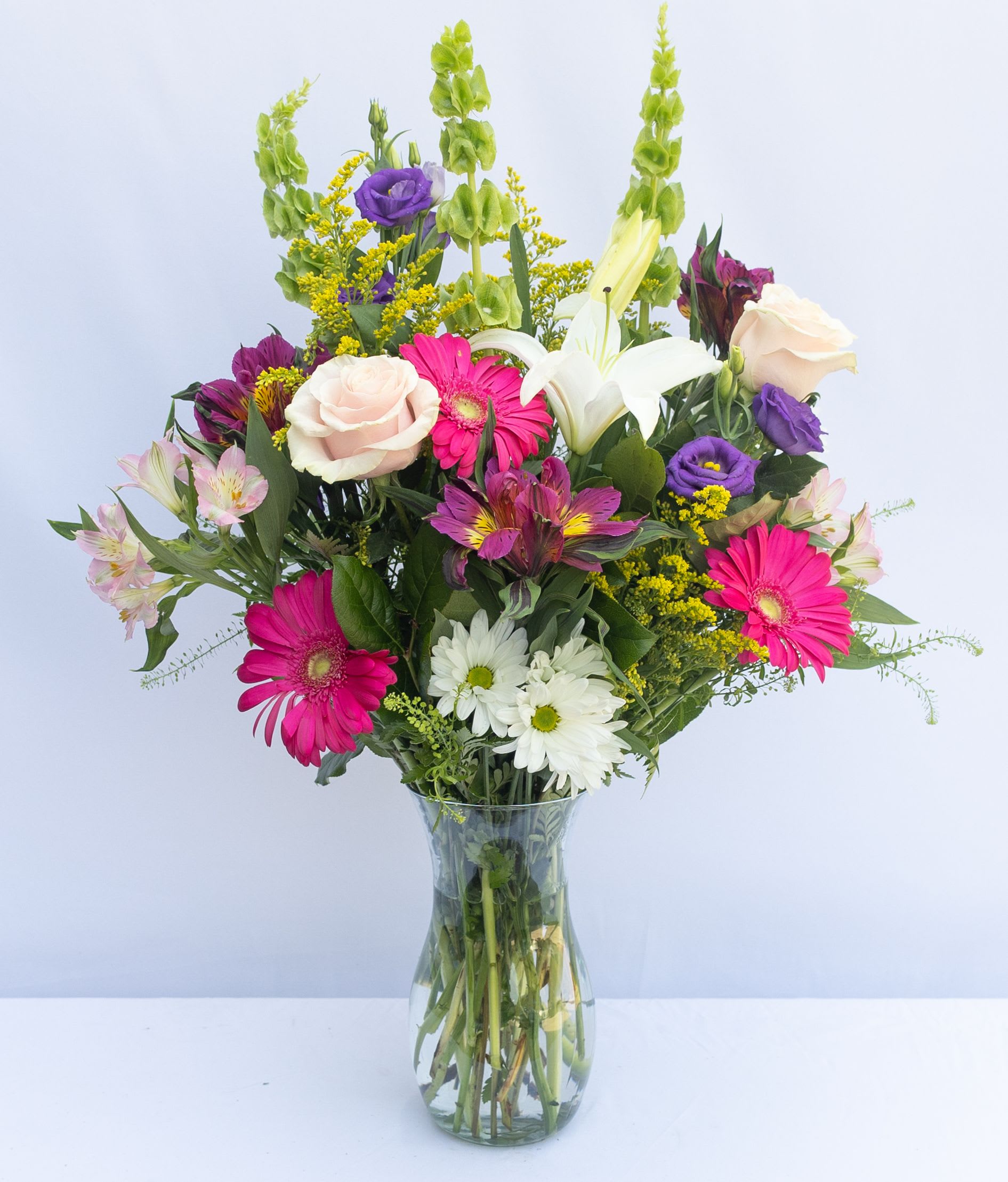 Mixed bouquet of pink, white, purple, and yellow flowers in a glass vase
