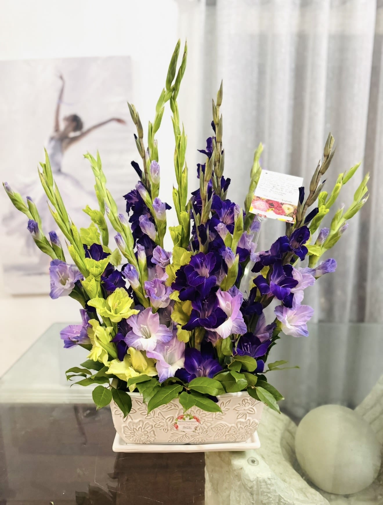 Purple  - Please Note: We may use a different vase.  A vase filled with gladiolus is a striking and elegant display- tall, graceful, and full of meaning. Gladiolus, with their long, sword-like stems and rows of bold blossoms, symbolize strength of character, integrity, and remembrance.  Each bloom opens upward in a poetic sequence- a rise from earth to sky, from grief to hope. Whether in soft pastels or vibrant hues, the gladiolus brings a sense of nobility and resilience, making it a powerful choice for commemorating a loved one or gracing any meaningful occasion.  