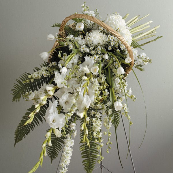 White floral basket arrangement with cascading blooms and a wicker handle