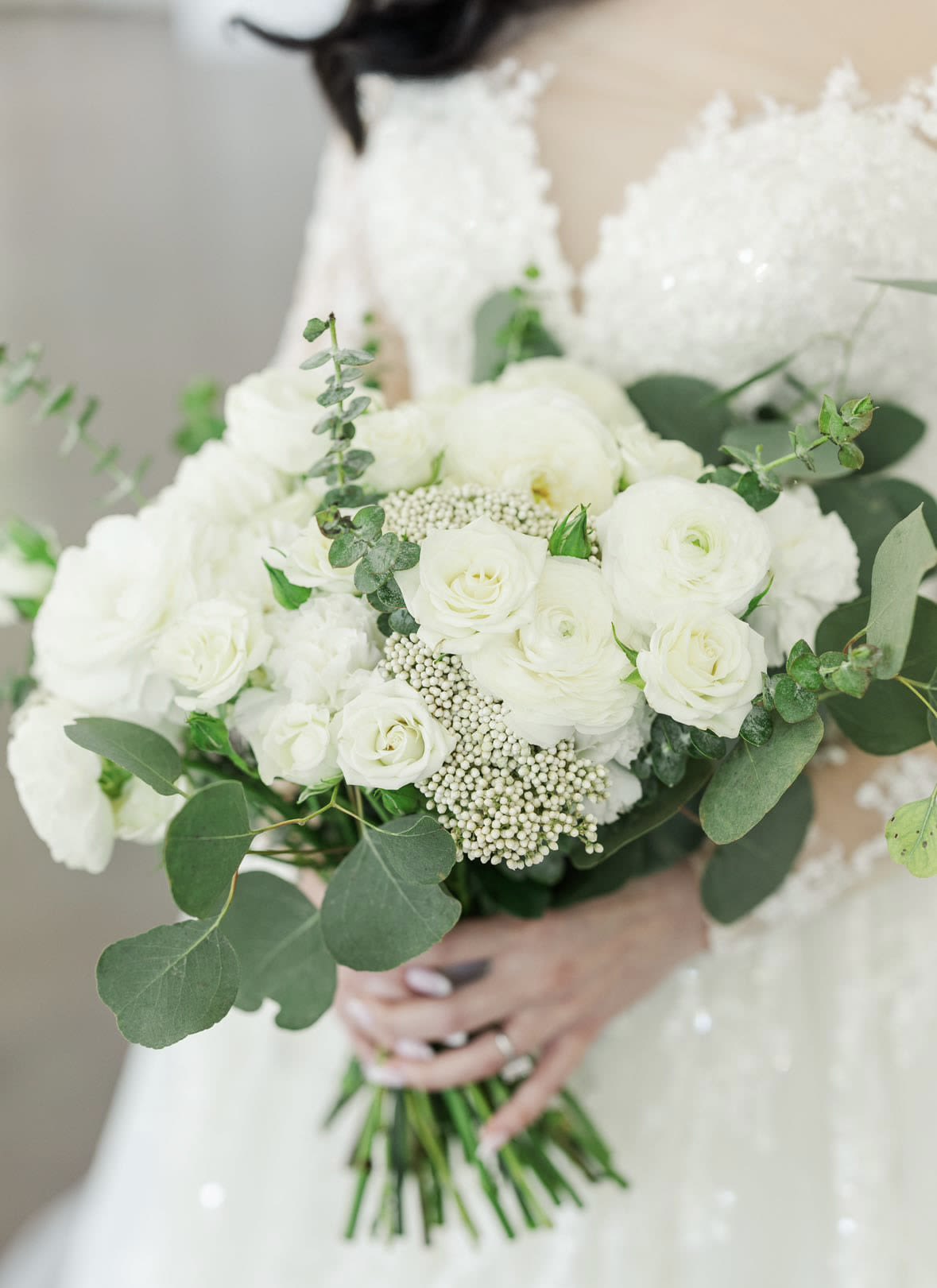 Bride holding a white bouquet with roses and greenery