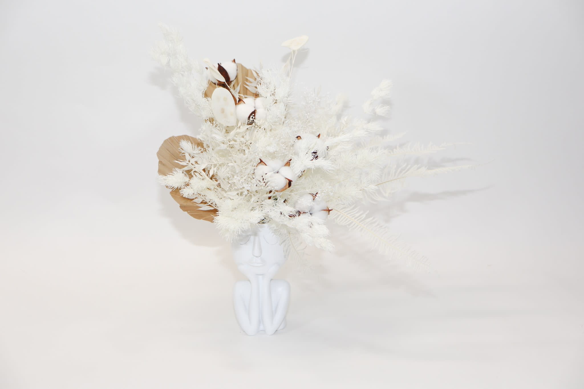 White floral arrangement in a white face-shaped vase