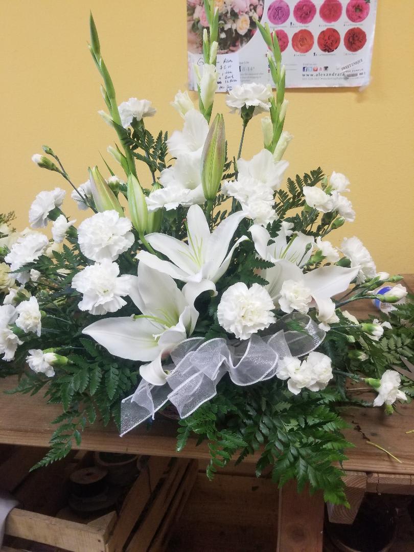 White lilies and carnations in a low arrangement with a silver ribbon