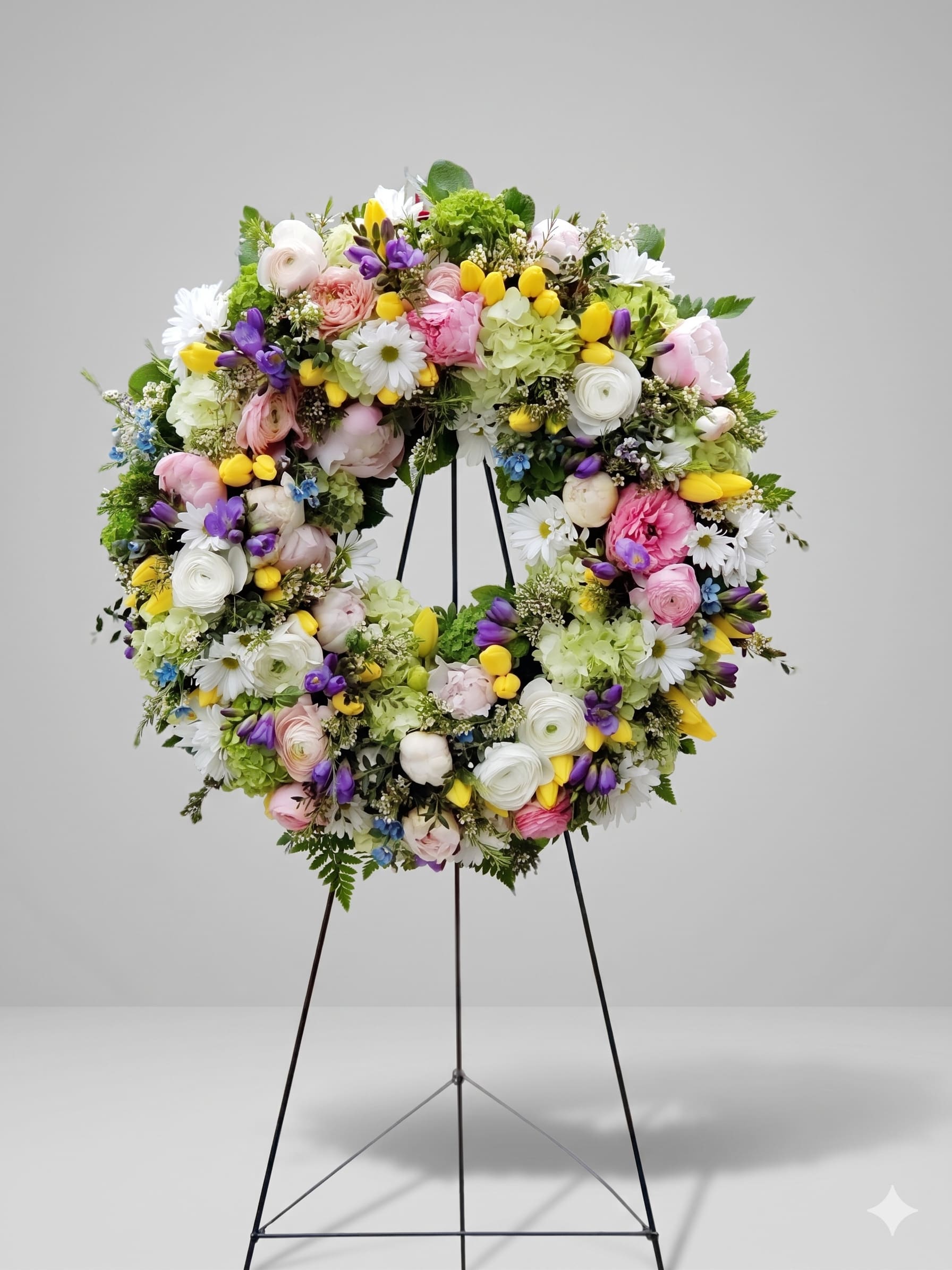 BP36 - Spring Serenity Wreath - A graceful tribute featuring soft pastel blooms, including delicate roses, tulips, and hydrangeas, accented with lush greenery.