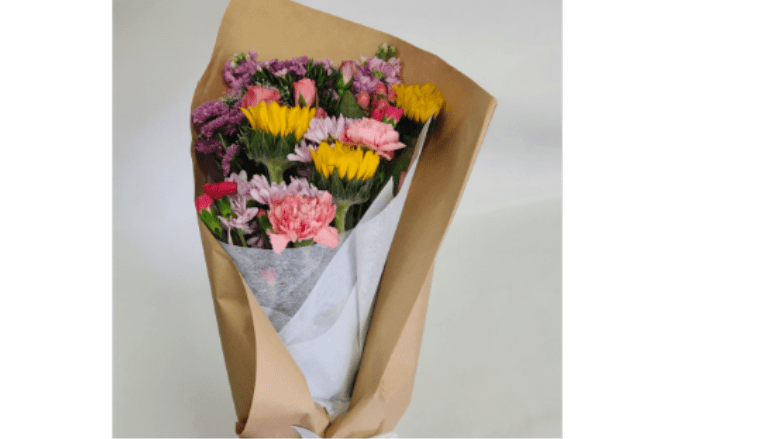 Bouquet of pink, purple, and yellow flowers wrapped in brown paper