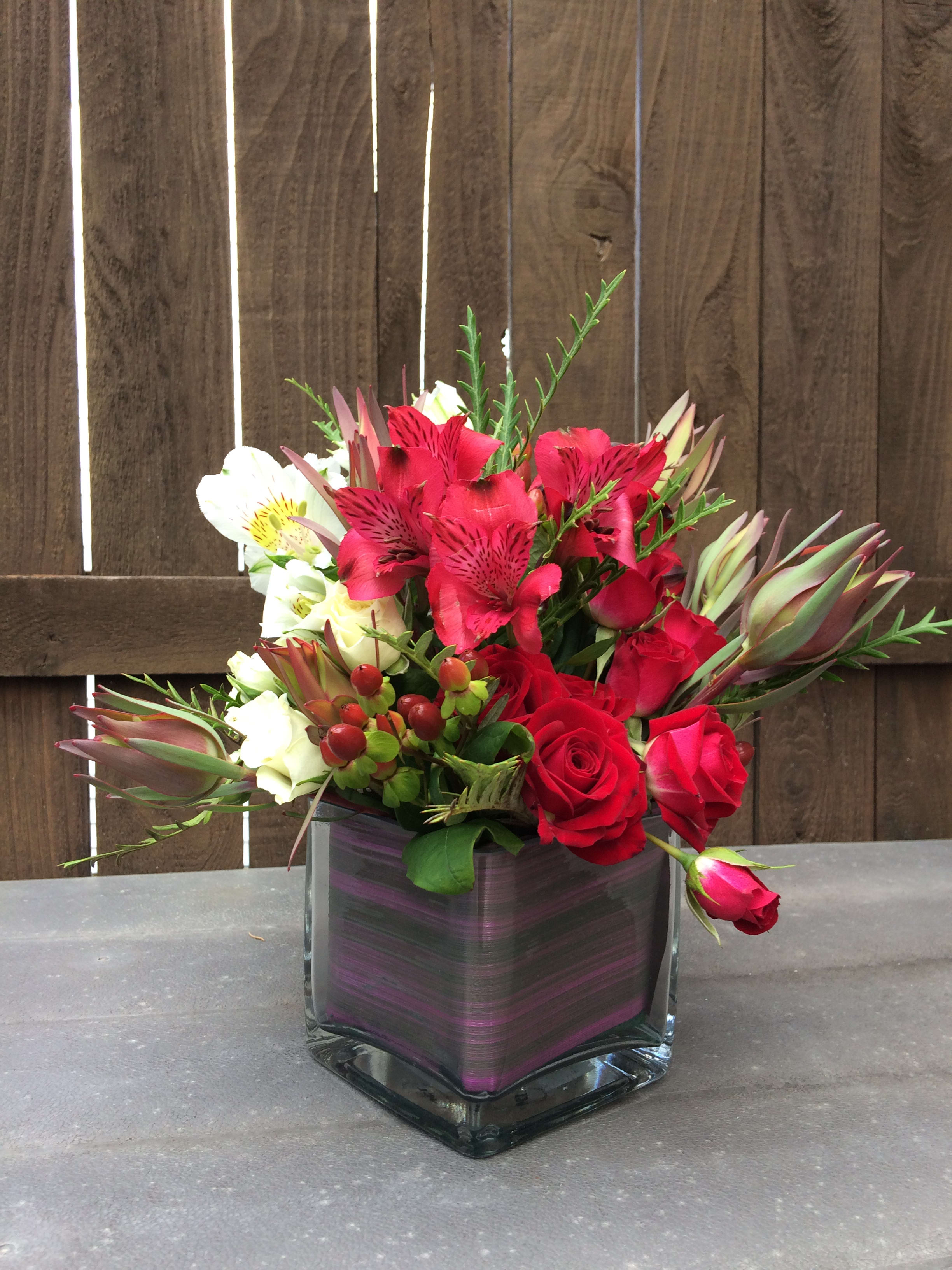 Red roses and white alstroemeria in a square glass vase