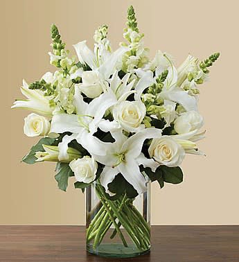 White lilies and roses arranged in a clear glass vase