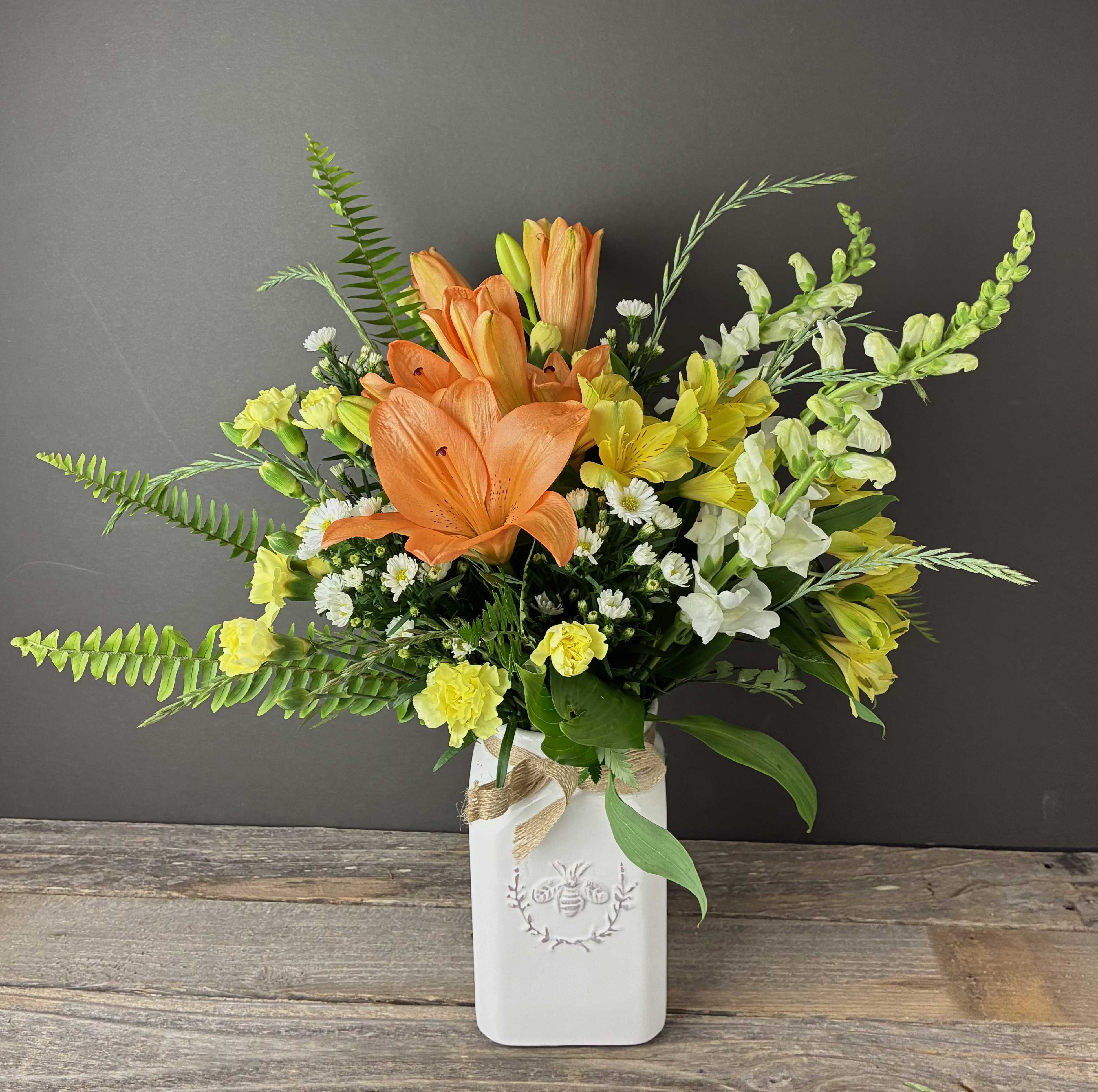 Bee Happy - Our Bee Happy arrangement features breezy blooms in shades of yellow, orange, and white in a white ceramic vase adorned with a bee. Perfect for sending a smile or livening up your space!