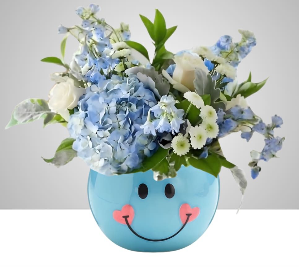 Sky Blue Smiles - Blue hydrangeas, white roses, daisies and delphinium in a cheerful blue ceramic pot with a smiling face and pink heart cheeks-playful, pastel charm for birthdays, get-well, or just because.