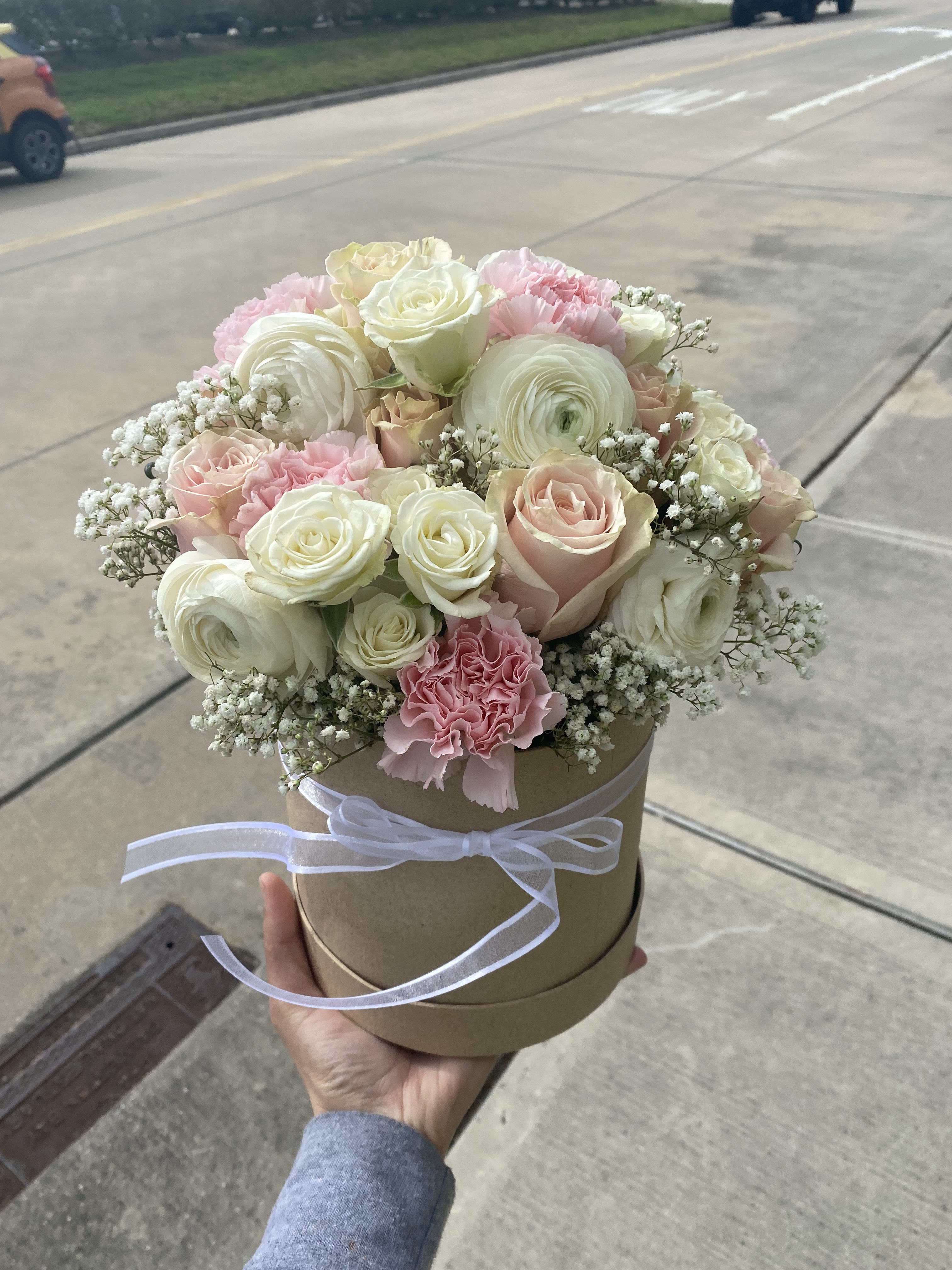 Round bouquet of pink and white roses in a ribbon-tied hat box