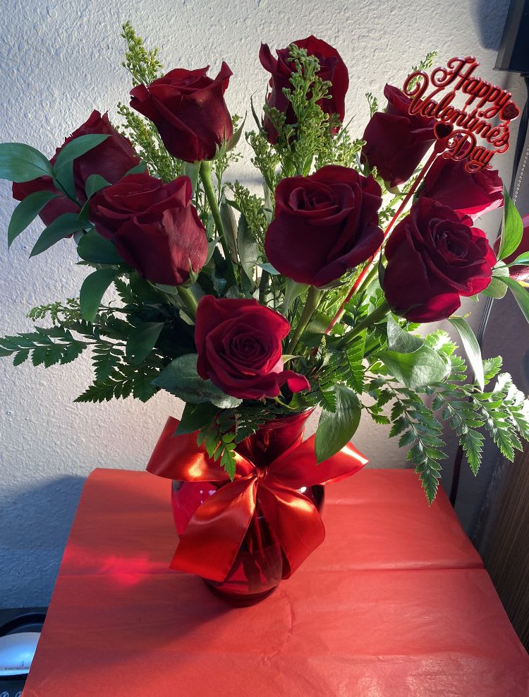 Bouquet of red roses in a glass vase with a Valentine sign