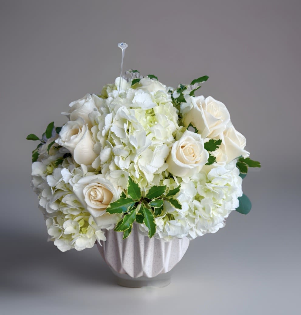 " Harmony " Flower Arrangement  - Beautiful white hydrangea arrangement. It's created with Ecuadorian white roses, seasonal foliage, fresh hydrangeas. It includes a pretty ceramic vase in white tones . Medium Size It's a round arrangement. Classic style. Share Joy Share Flowers.