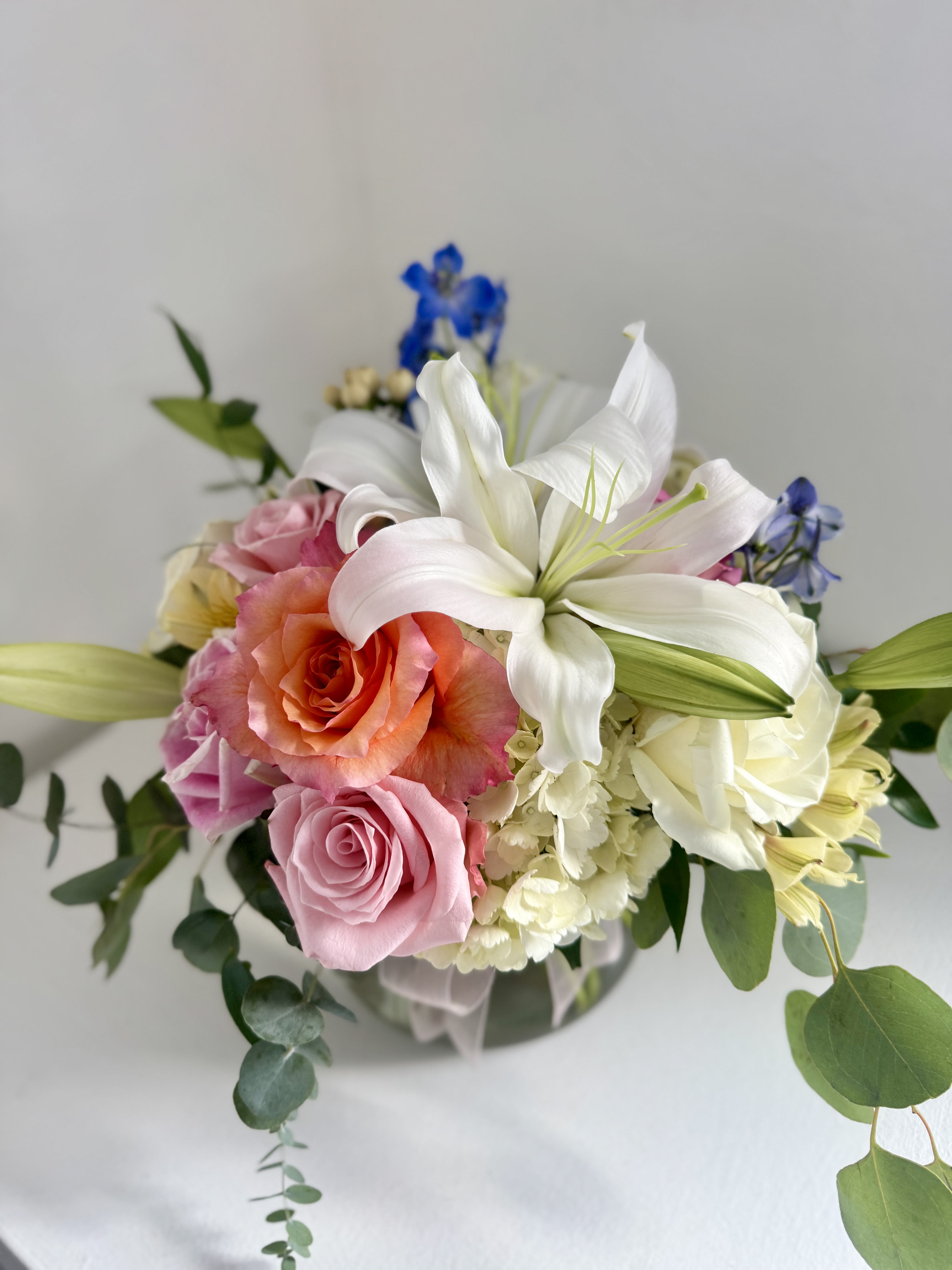 Bouquet of pink and white roses with a white lily in a glass vase