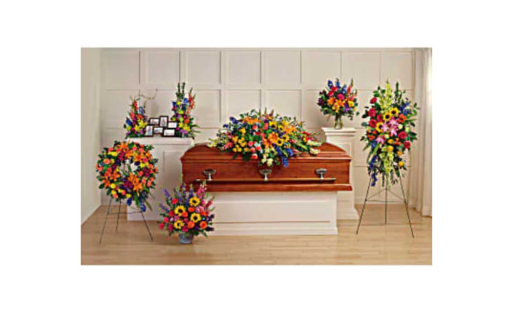 Colorful funeral casket spray with matching standing floral arrangements