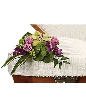 Purple and green floral spray on a white casket