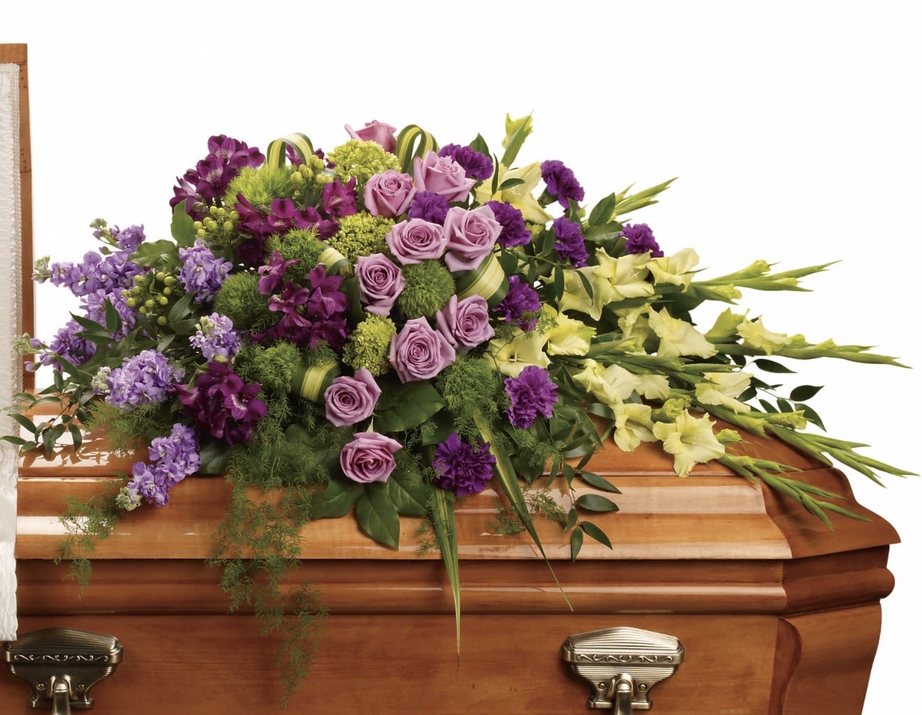 Reflections of Gratitude Casket Spray - A sweeping display of lavender roses and pale green gladiolus, this casket spray offers a gentle, dignified tribute perfect for a funeral or memorial service. The arrangement's name and purpose-casket spray for a funeral-are reflected in its formal yet uplifting palette of purple, pink, yellow, and green, designed to comfort the person you're honoring and convey heartfelt gratitude.  Dense clusters of lavender roses and purple blooms gather at the center for a rich focal point, while long gladiolus stems extend outward to the right for an elegant, sweeping silhouette that sits directly on a wooden casket. The composition is layered and full, with touches of soft pink and fresh greenery adding contrast and a soothing, textured finish.  Made to communicate respect and remembrance, this spray is ideal for family members, close friends, or anyone whose life you wish to celebrate with grace. It arrives assembled on a casket base sized to drape across the top; recommend coordinating with the funeral director for placement and timing to ensure it's in place for the service.