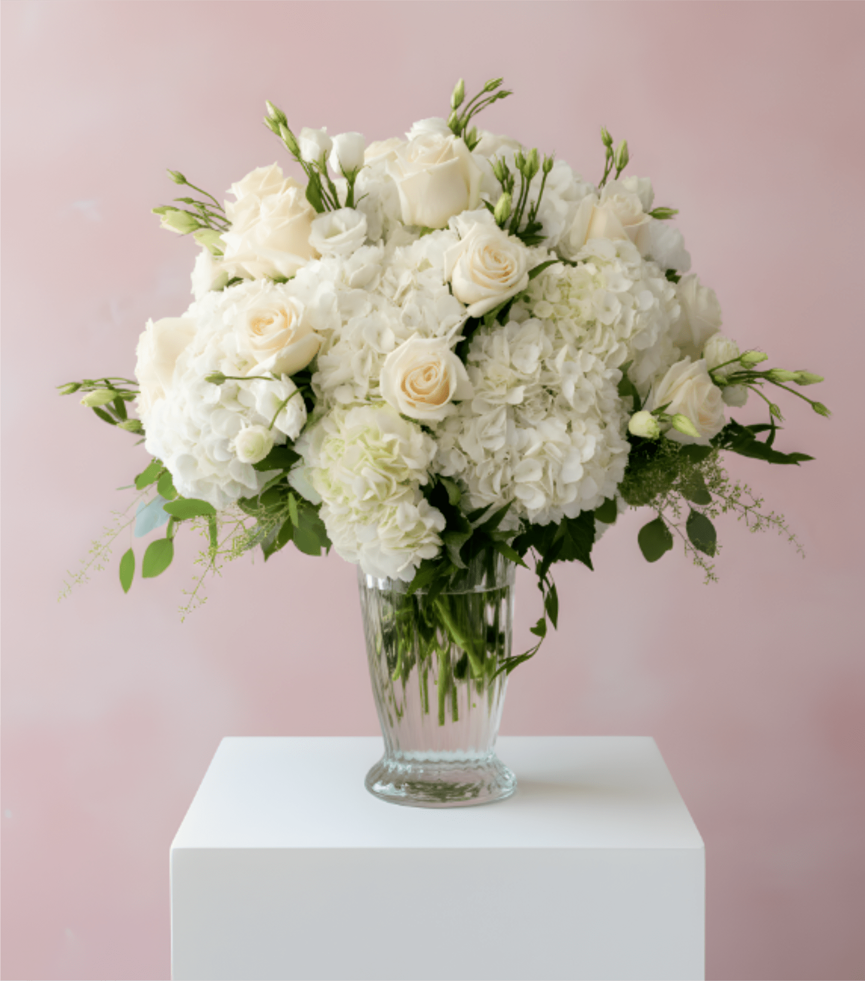 White roses and hydrangeas arranged in a clear glass vase