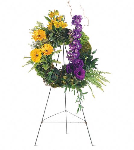 Standing floral wreath with yellow and purple flowers on a metal easel