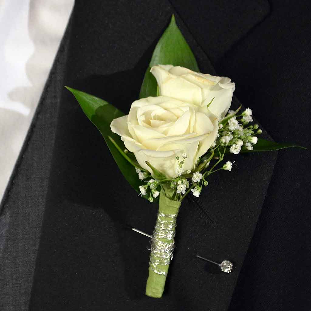 White rose boutonniere with baby's breath on a black suit lapel