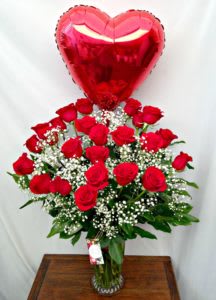 Tall vase of red roses with white baby’s breath and a red heart-shaped balloon.