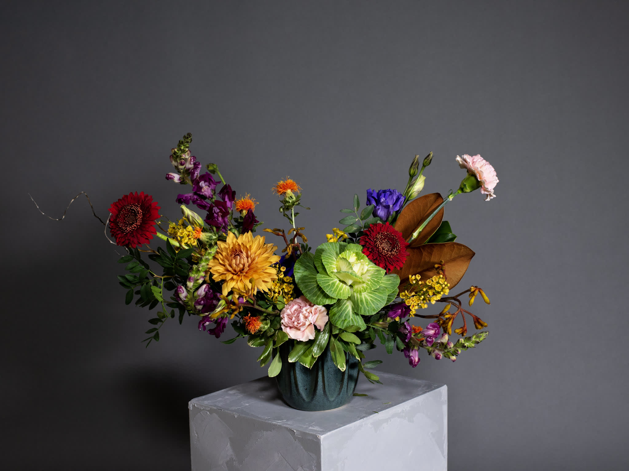 Colorful mixed flower arrangement in a dark vase on a pedestal