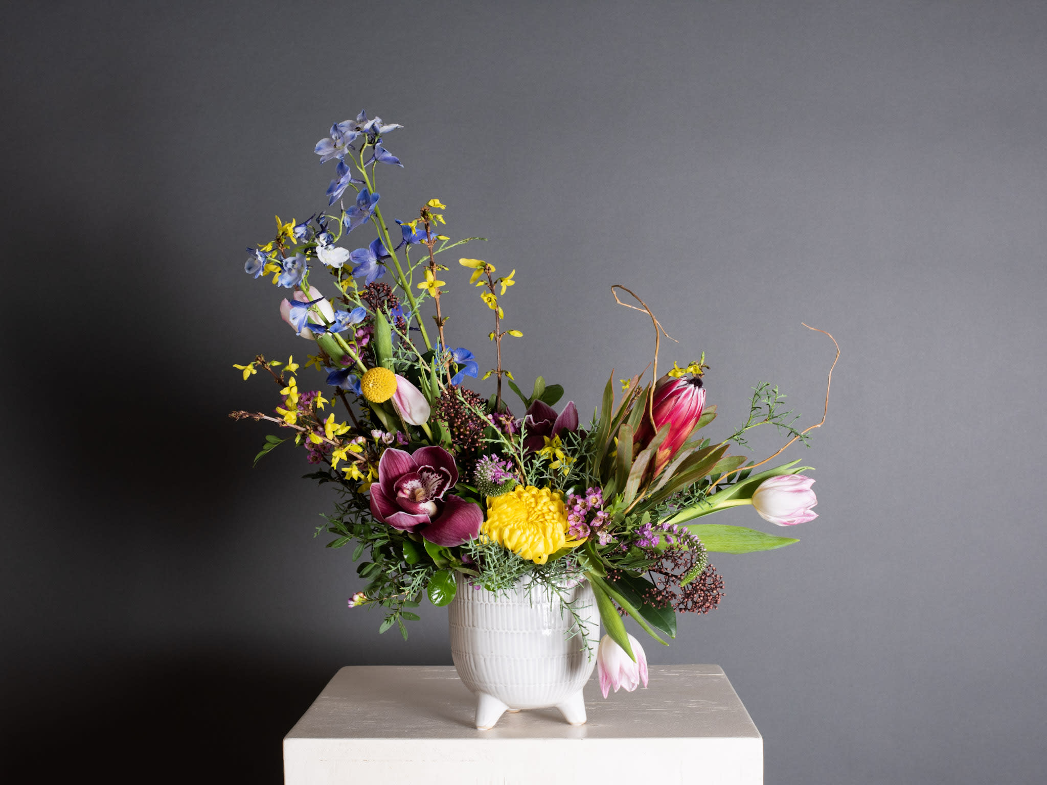 Colorful mixed flower arrangement in a white ceramic vase