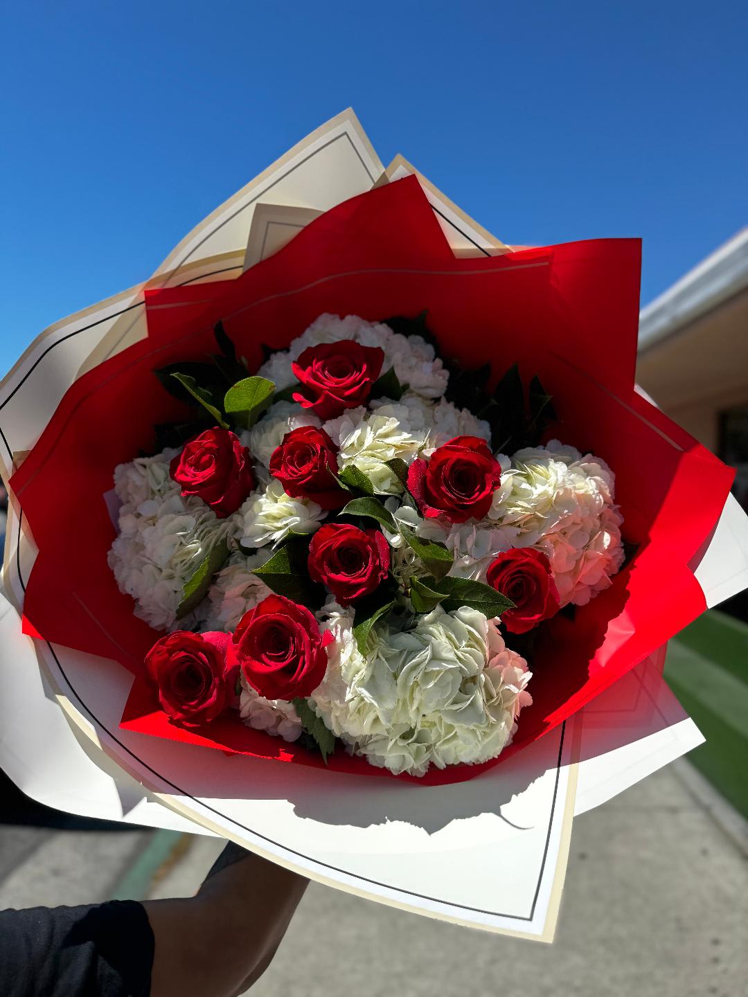 Bouquet of red roses and white hydrangeas wrapped in red and white paper