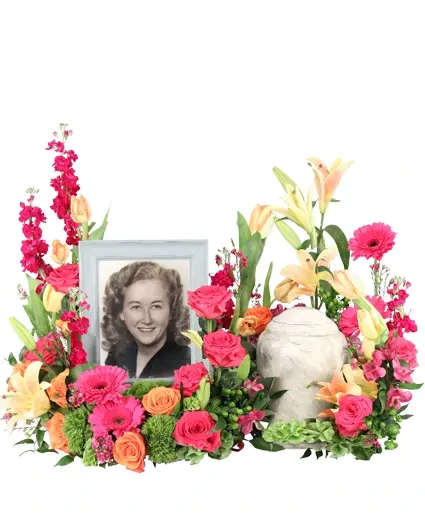 Vibrant Hope Cremation Flowers - Vibrant Hope is a stunning memorial arrangement brimming with hot pink roses and gerberas, complemented by peach tulips and lilies. Each bloom exudes radiant energy, symbolizing the enduring spirit of a loved one. As vibrant hues intertwine, this arrangement is a testament to the joy and beauty they have brought  Includes: Round Mache Wreath, Cut In Half With Halves Placed Next To Each Other, Italian Ruscus, Green Trick Dianthus, Hot Pink Gerberas, Green Hypericum, Peach Lilies, Hot Pink Roses, Purple Stock, Peach Tulips, Pink Waxflower, Orange Roses.