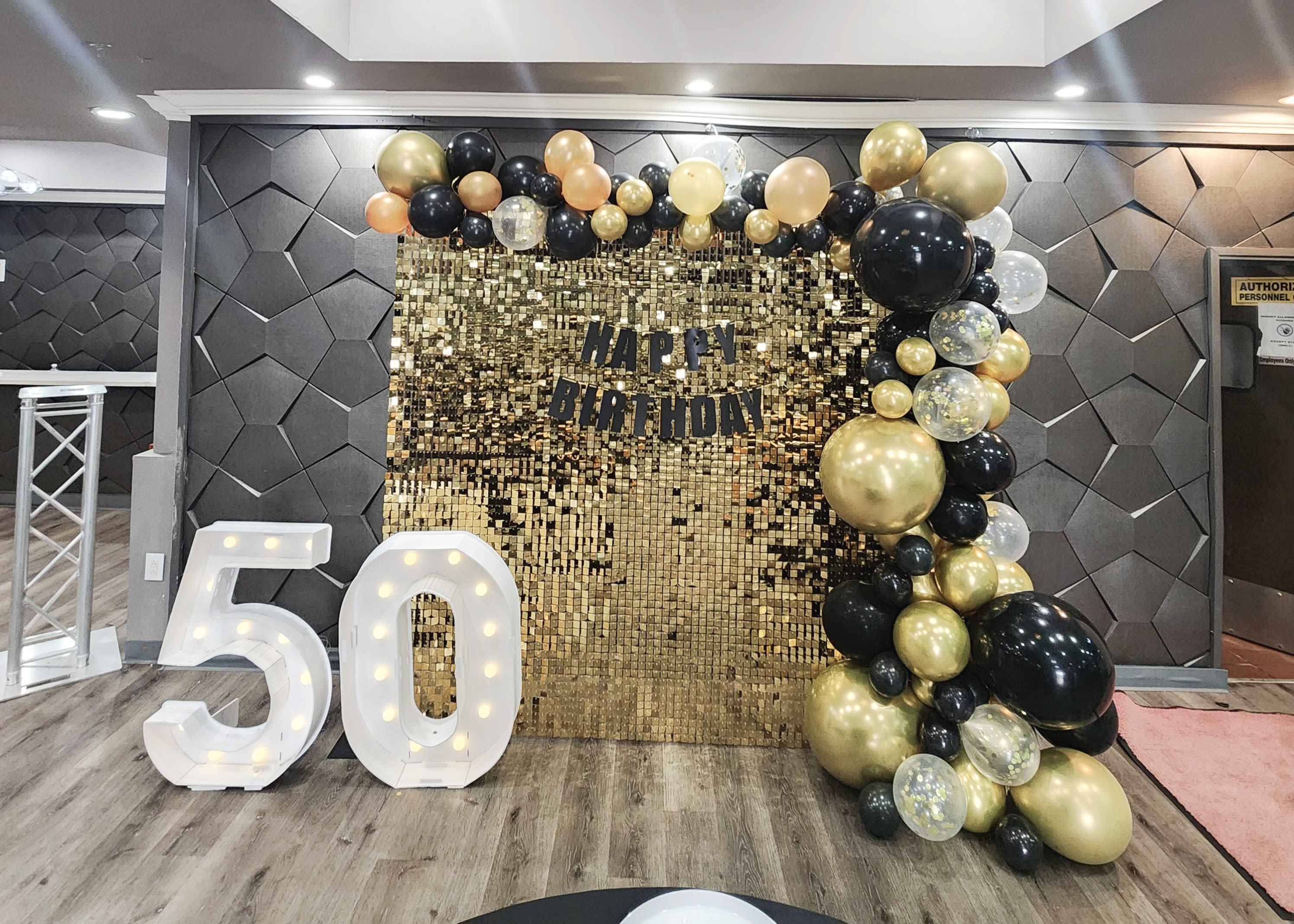 Birthday backdrop with gold and black balloons and large lit number 50