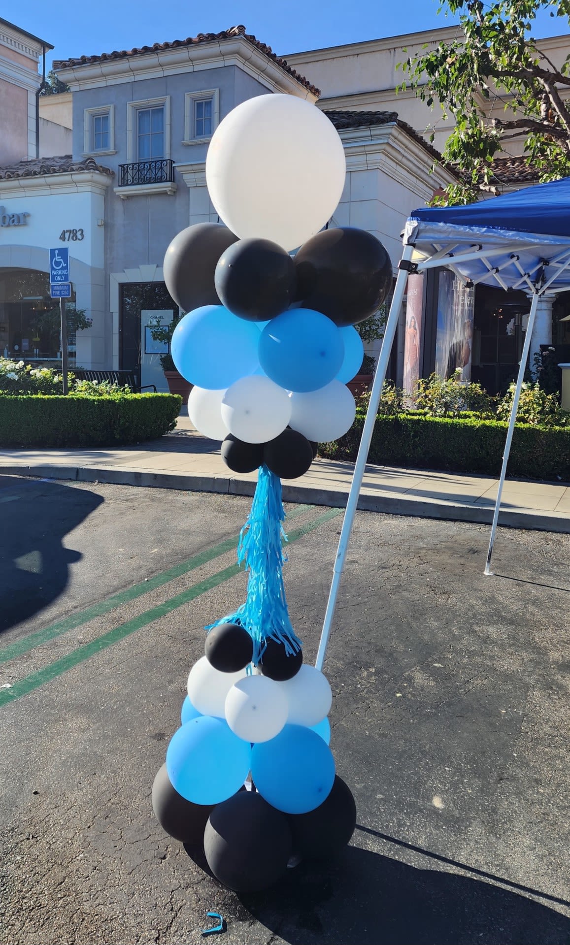 Tall balloon column in black, white, and blue with a blue tassel