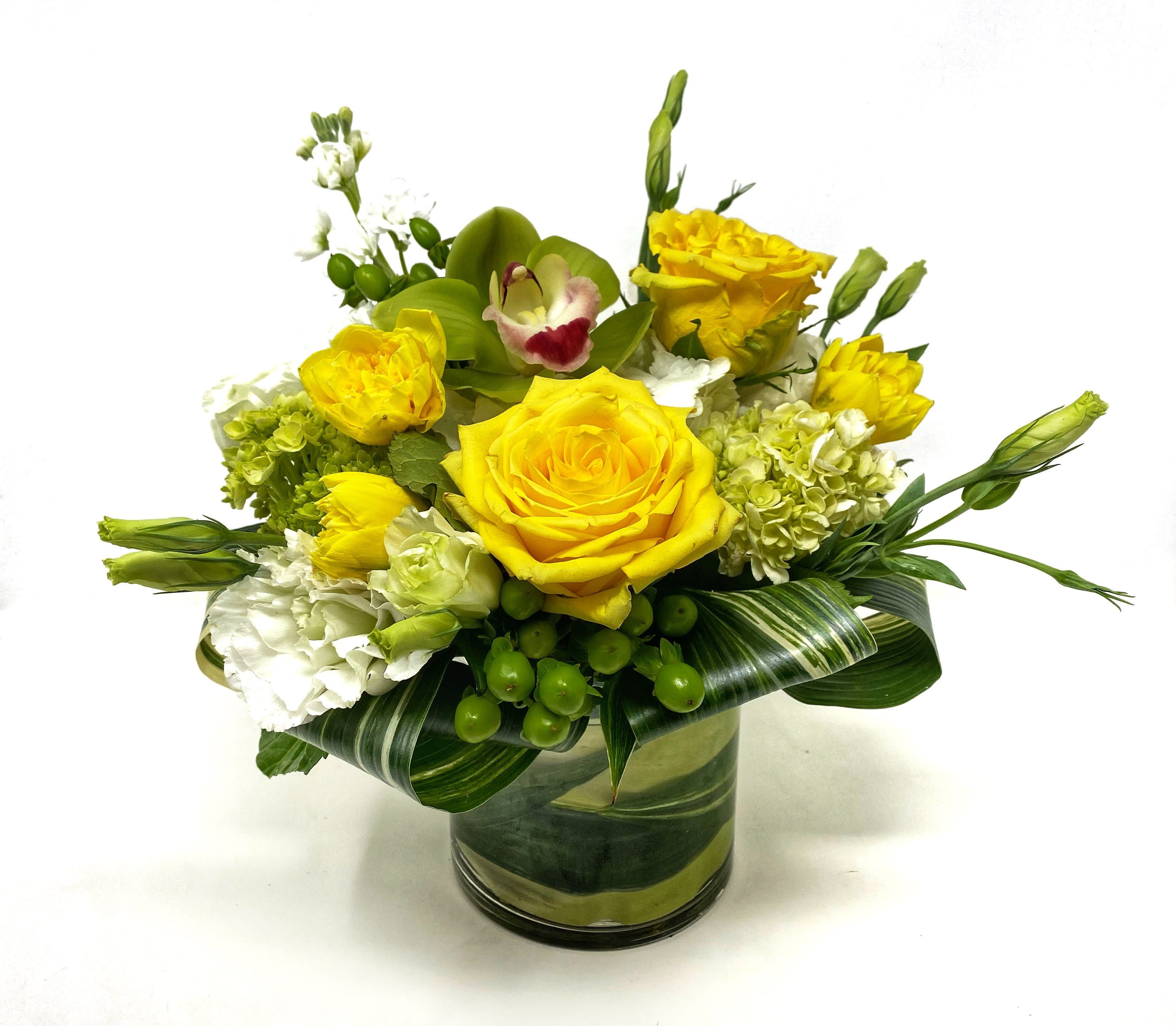 Yellow roses and white blooms arranged in a glass vase