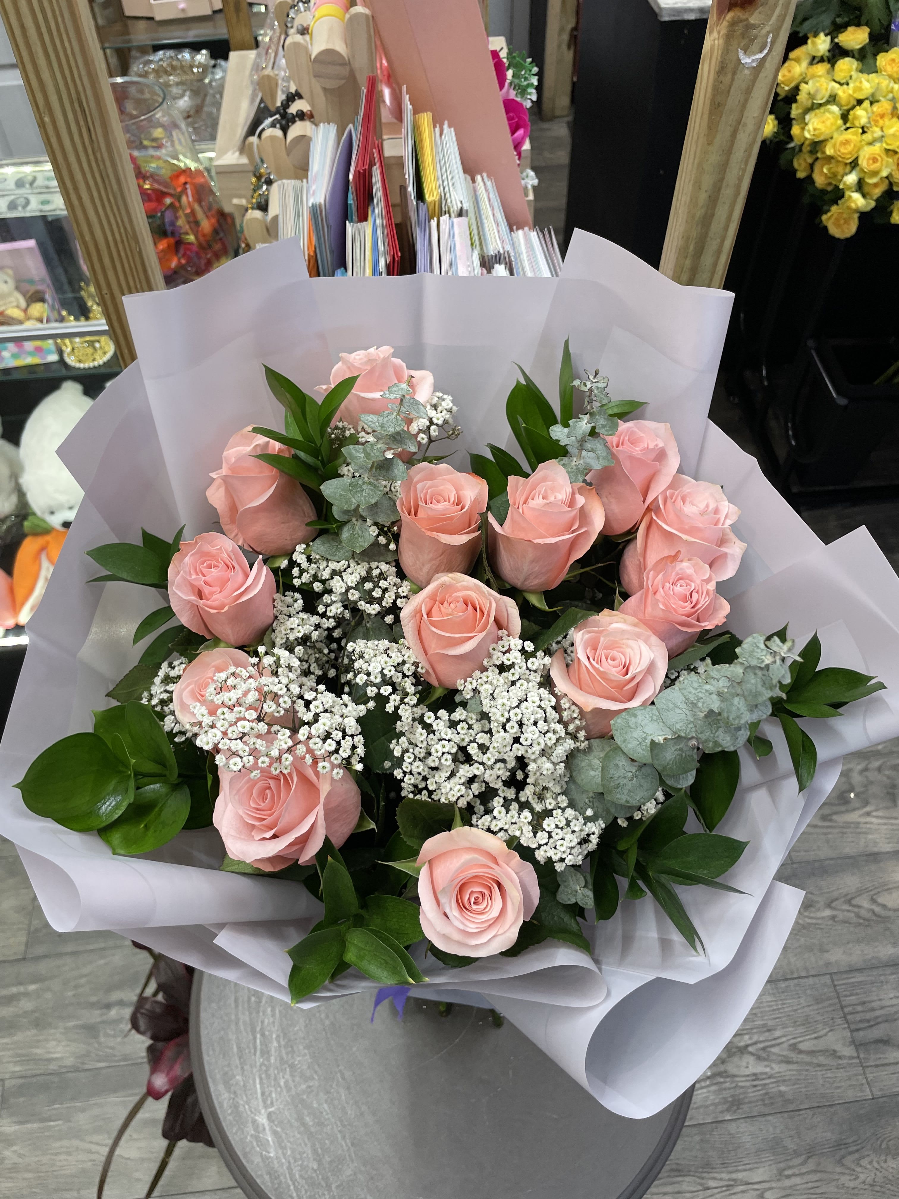 Bouquet of pink roses with white filler flowers wrapped in white paper