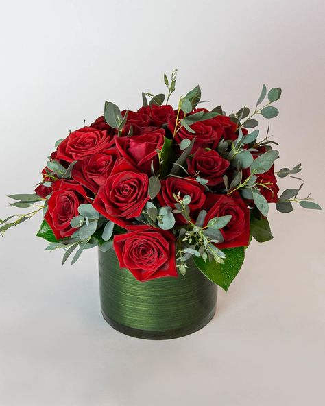 Red roses arranged in a green cylindrical vase