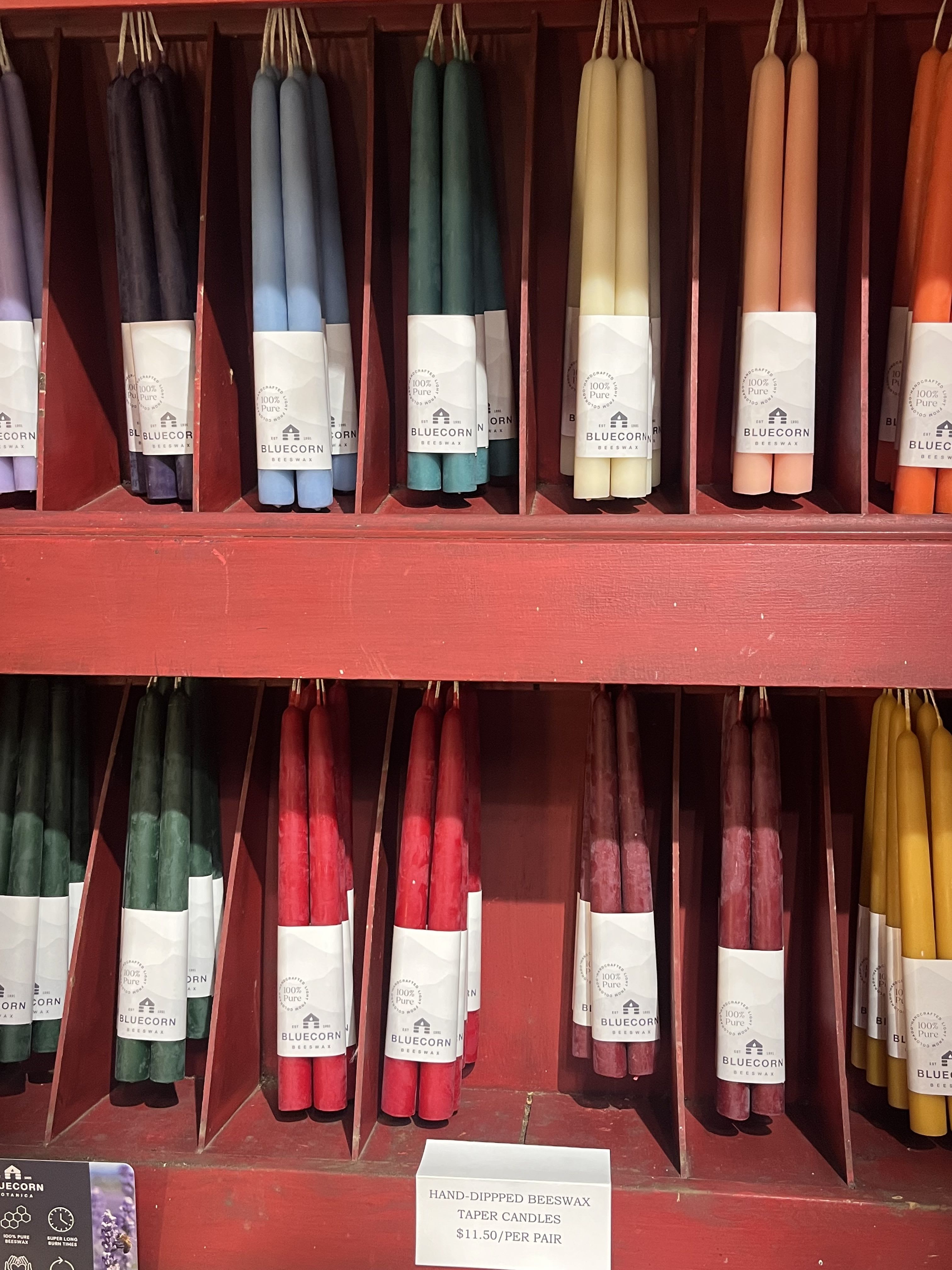 Assorted taper candles in a red display shelf