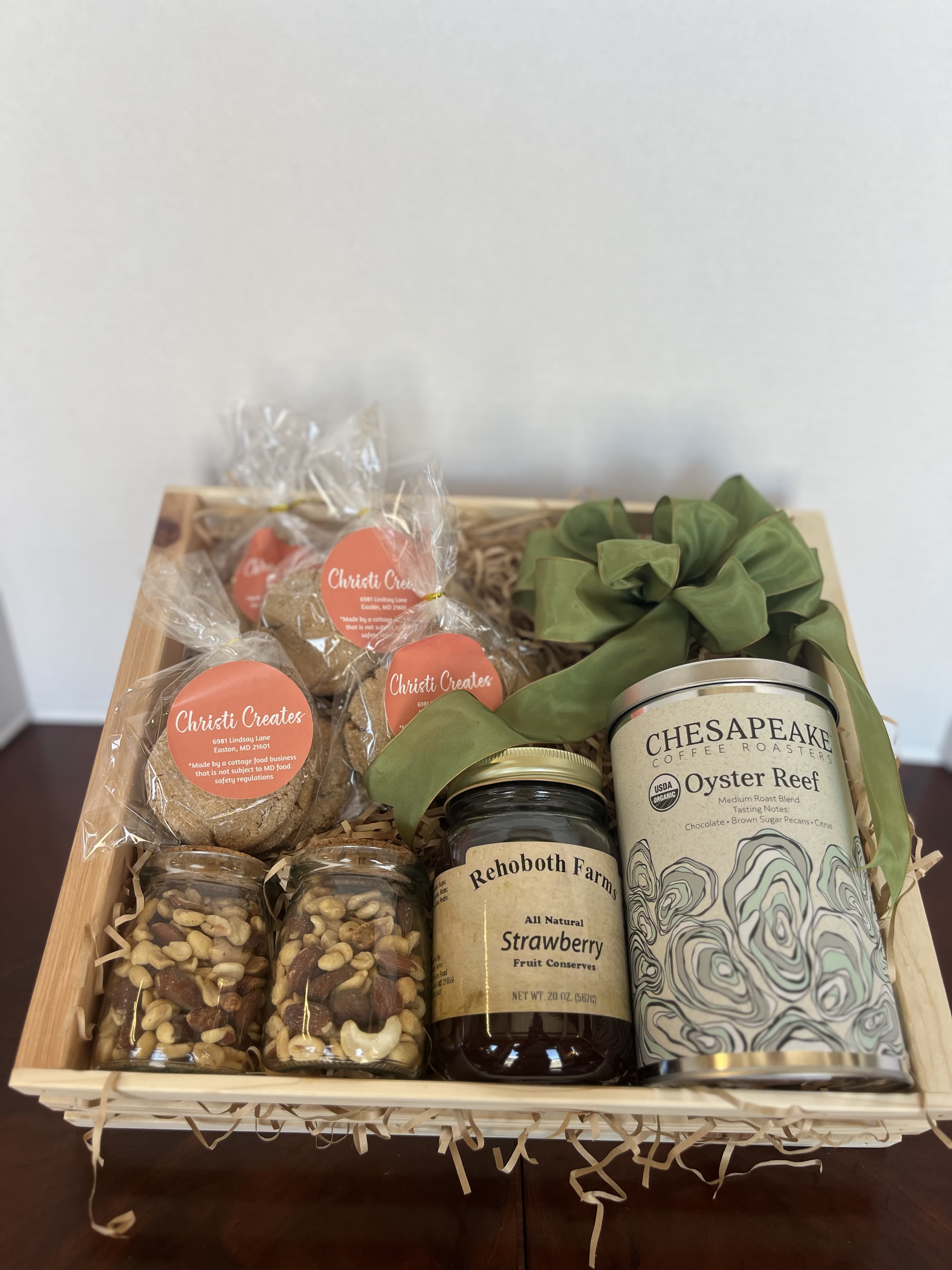 Gift basket with coffee, jam, cookies, and snack jars tied with green ribbon